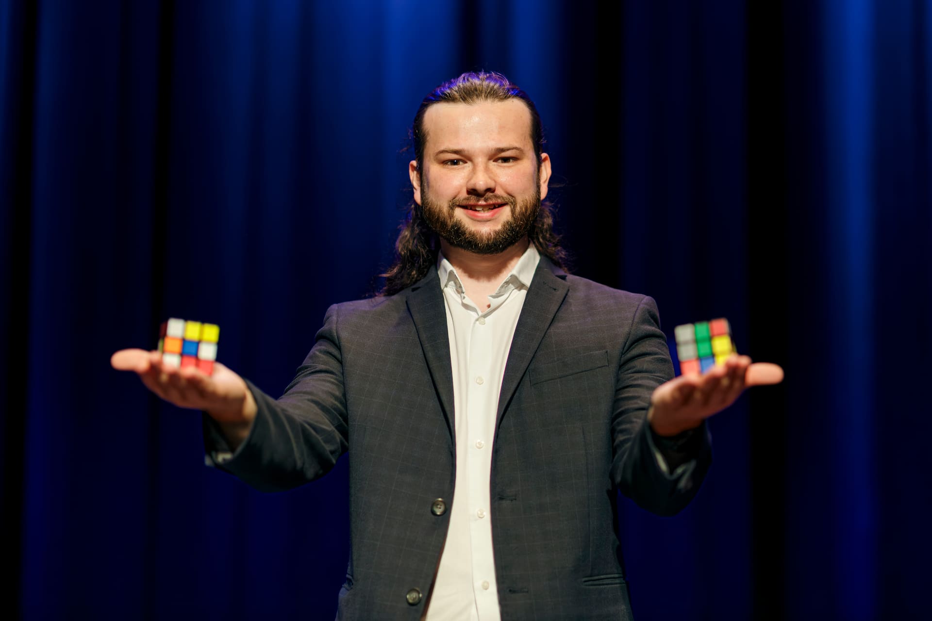 Magician Callum McClure holding a Rubik's cube on each open palm