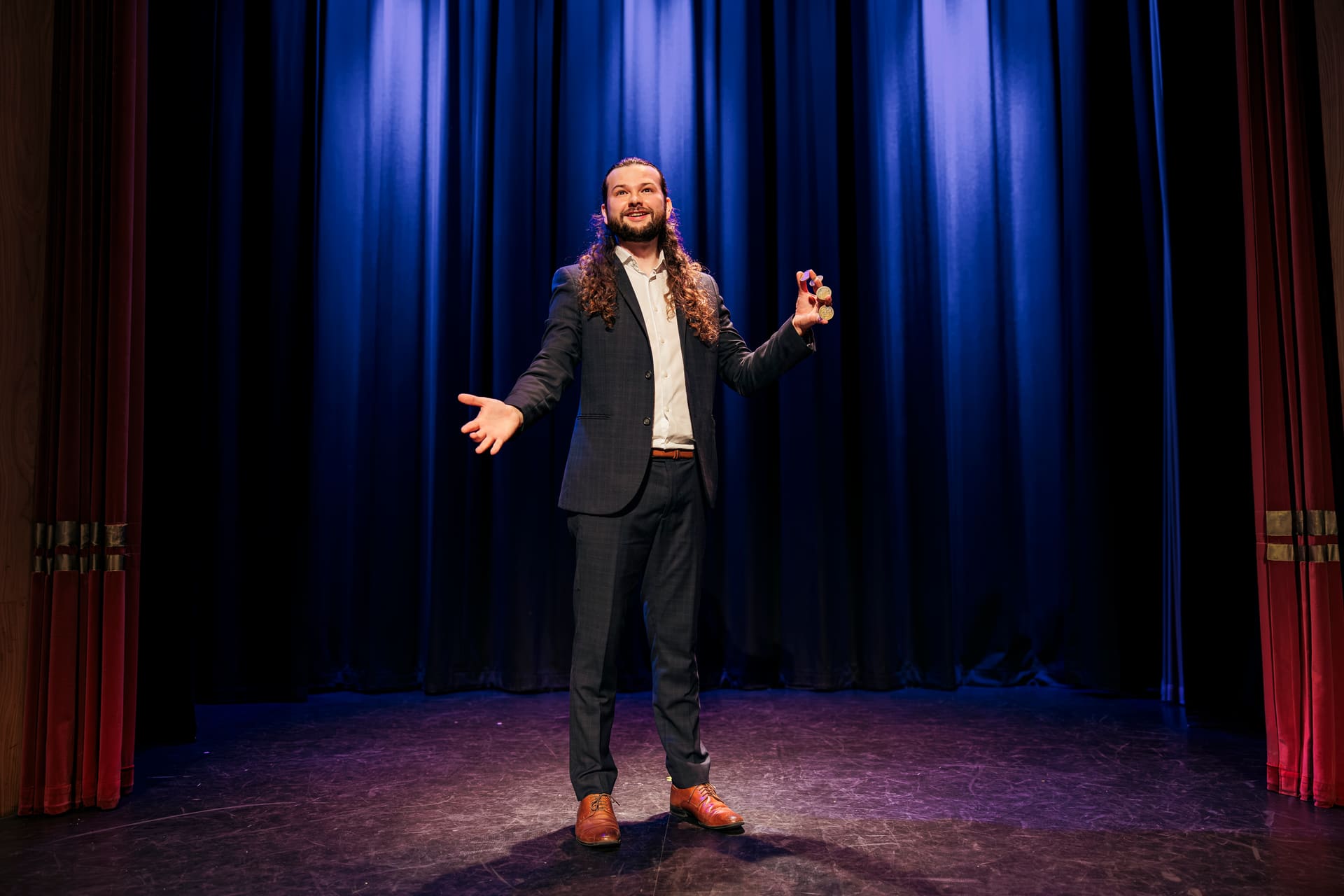 Magician Callum McClure holding a stack of coins at his fingertips on stage