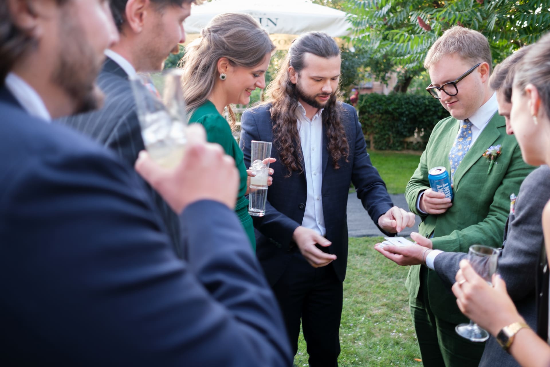 Guests gathered around a table watching a card trick at a drinks reception