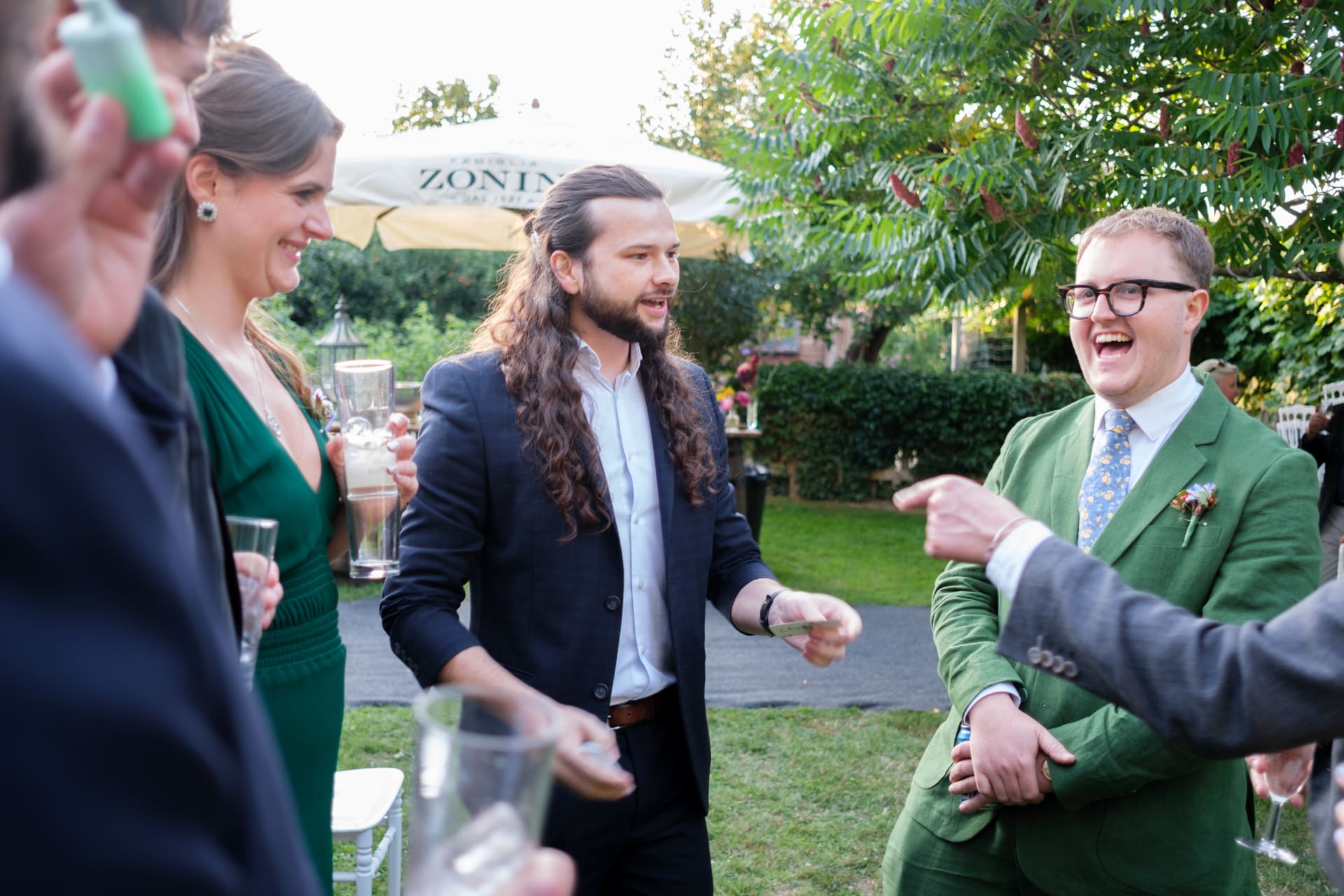 A guest laughing as magician Callum McClure performs close-up magic at an outdoor drinks reception